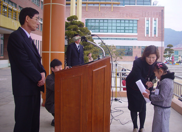 신입생대표로 입학선서를 하는 김현빈 어린이와 이를 지켜보는 김영렬 교장. 